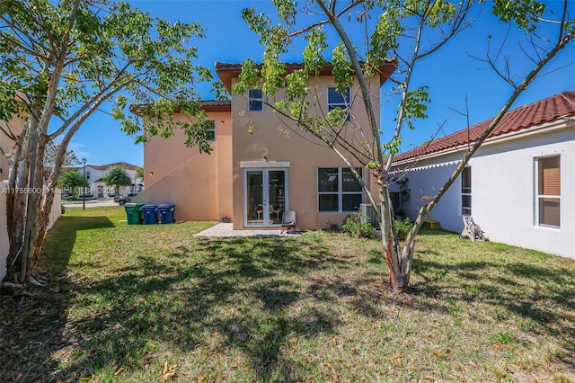 rear view of property featuring a yard, french doors, and stucco siding