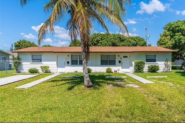 ranch-style house with fence, a front lawn, and stucco siding