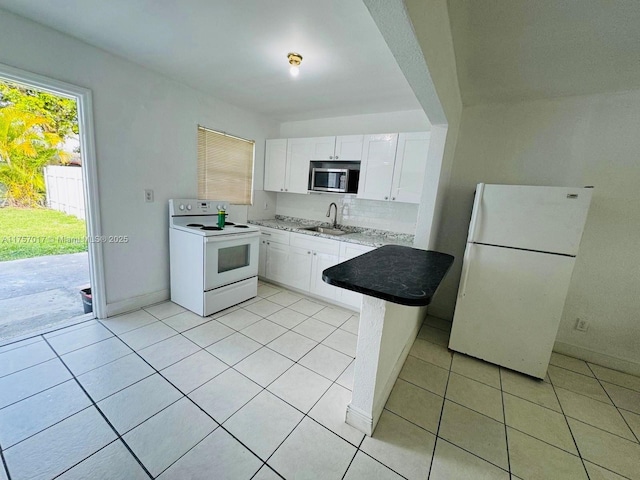 kitchen with light tile patterned floors, tasteful backsplash, white cabinetry, a sink, and white appliances