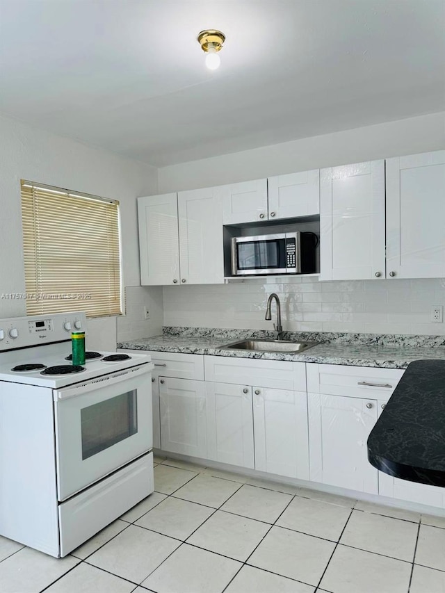 kitchen with a sink, stainless steel microwave, white cabinets, and electric stove