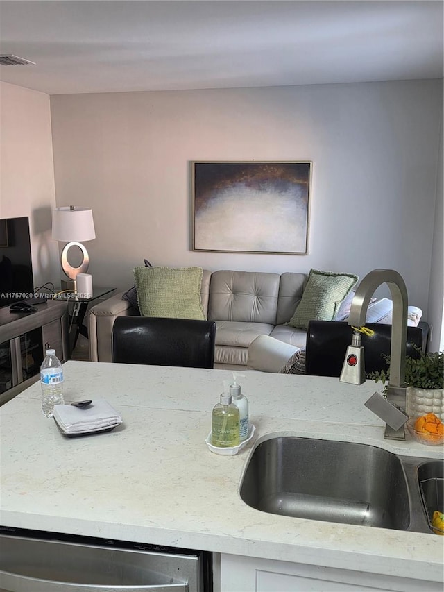 kitchen featuring dishwasher, a sink, visible vents, and light stone countertops