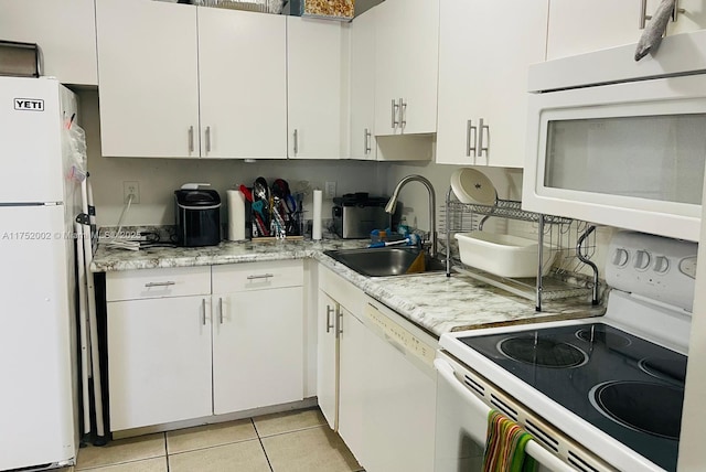 kitchen with white appliances, white cabinetry, a sink, and light tile patterned flooring