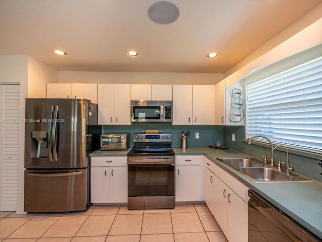 kitchen featuring a toaster, light tile patterned floors, stainless steel appliances, white cabinets, and a sink