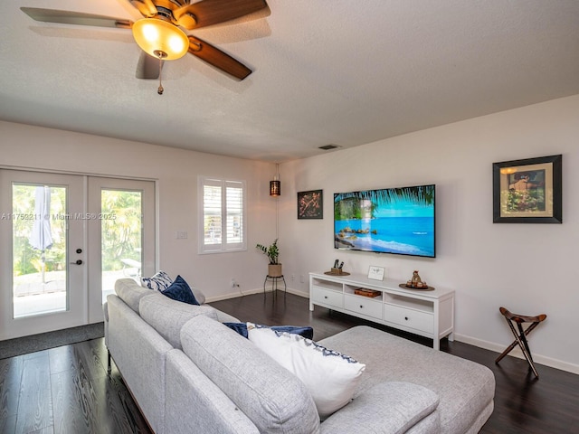 living area with a textured ceiling, dark wood-type flooring, visible vents, baseboards, and french doors