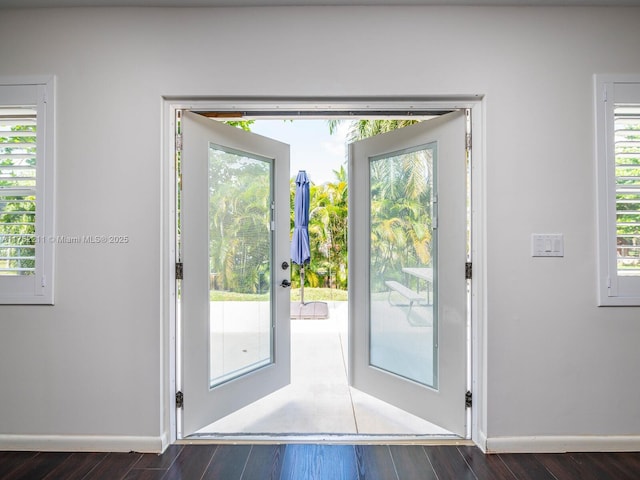 doorway featuring dark wood-style floors, plenty of natural light, and baseboards