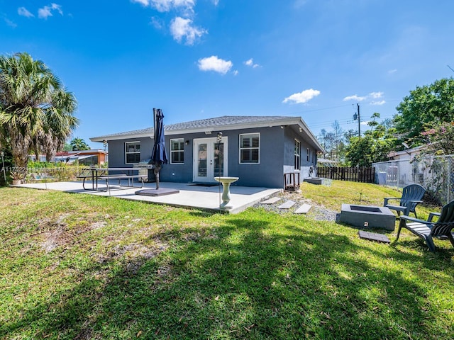 rear view of house with a patio, fence, a yard, french doors, and stucco siding