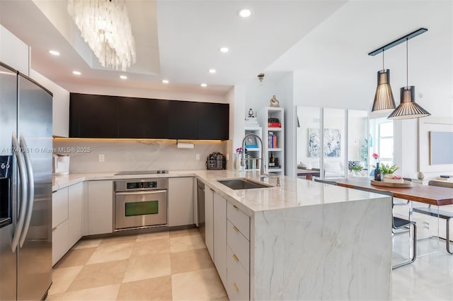 kitchen featuring a peninsula, a sink, appliances with stainless steel finishes, tasteful backsplash, and modern cabinets