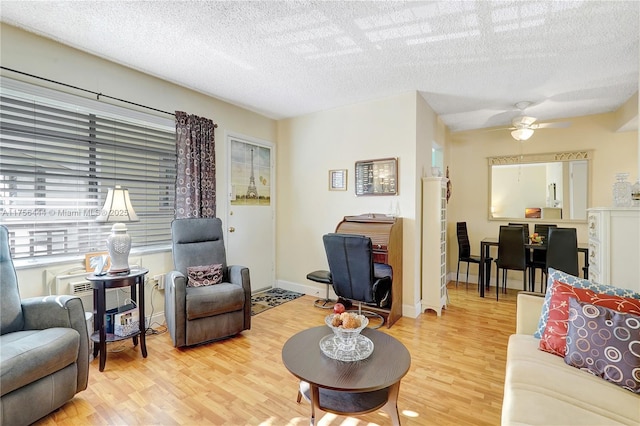 living area featuring ceiling fan, a textured ceiling, baseboards, and wood finished floors