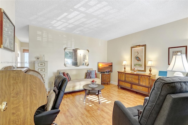 living room with light wood-style flooring, baseboards, and a textured ceiling