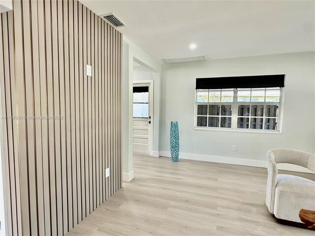 sitting room featuring light wood-style flooring, visible vents, and baseboards