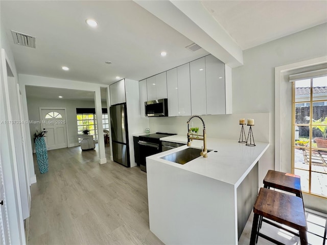 kitchen with stainless steel appliances, visible vents, a sink, and modern cabinets