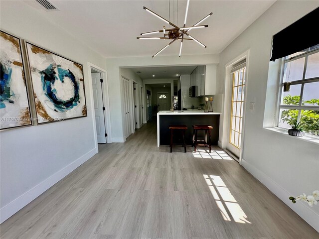 kitchen featuring visible vents, baseboards, light wood-style floors, light countertops, and a kitchen bar