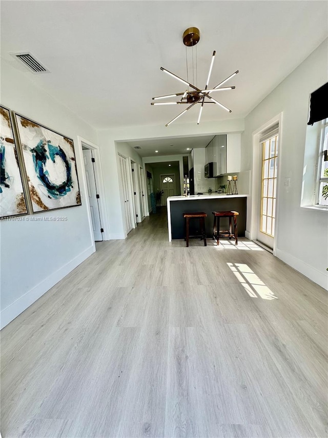 interior space featuring light wood finished floors, light countertops, visible vents, black microwave, and a kitchen bar