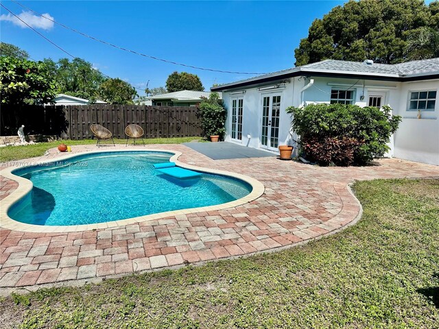 view of pool featuring a patio area, fence, glass enclosure, and a fenced in pool