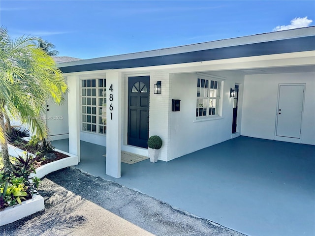 doorway to property featuring a carport and stucco siding