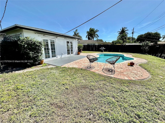 view of swimming pool featuring french doors, a fenced backyard, a patio, and a lawn