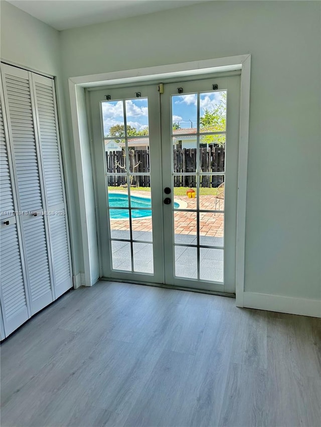 entryway with french doors, wood finished floors, and baseboards