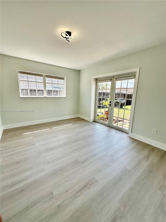 unfurnished room featuring baseboards, wood finished floors, and french doors