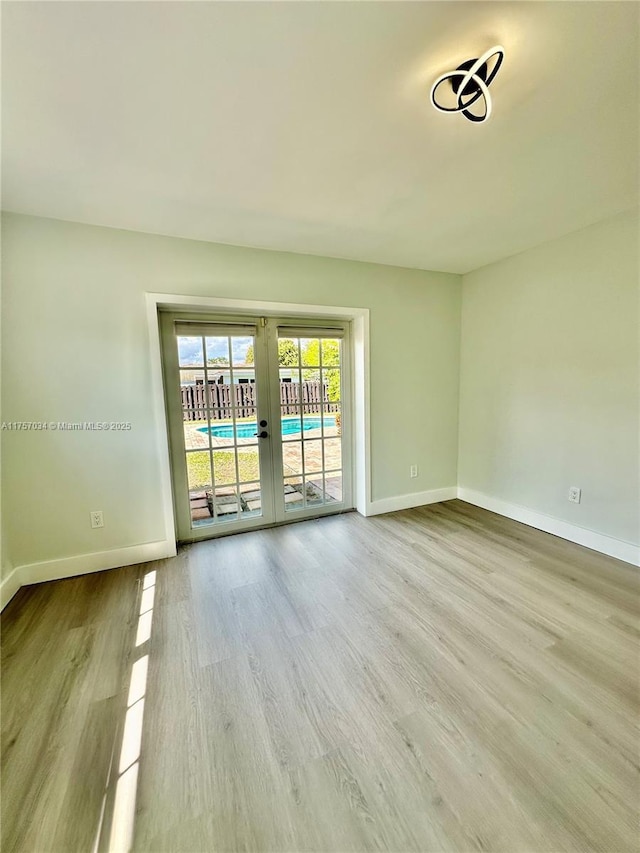 spare room with french doors, wood finished floors, and baseboards