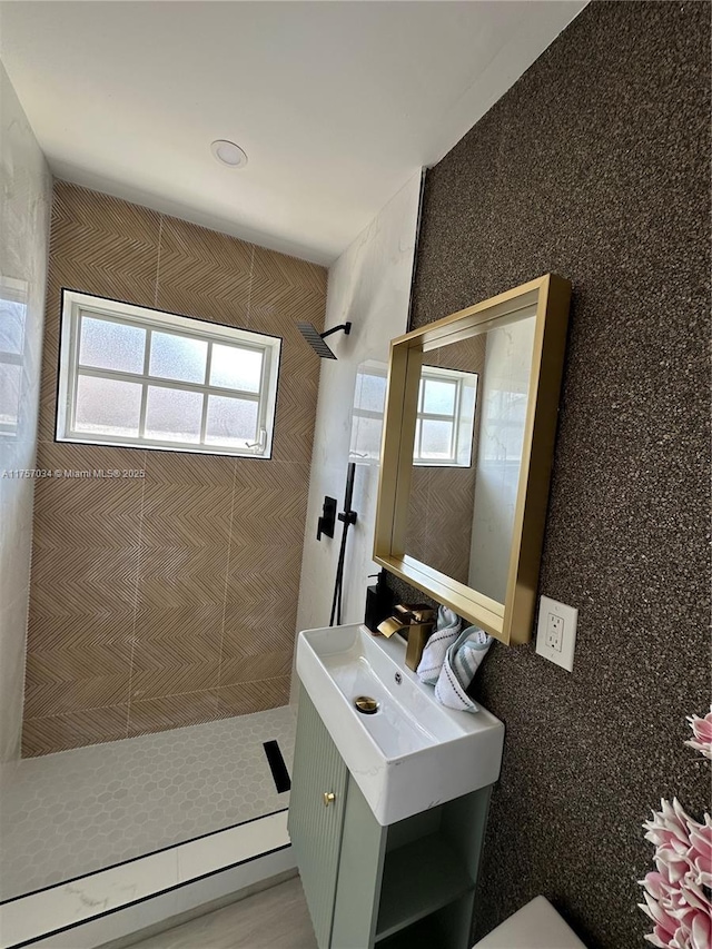 full bathroom with tiled shower and vanity