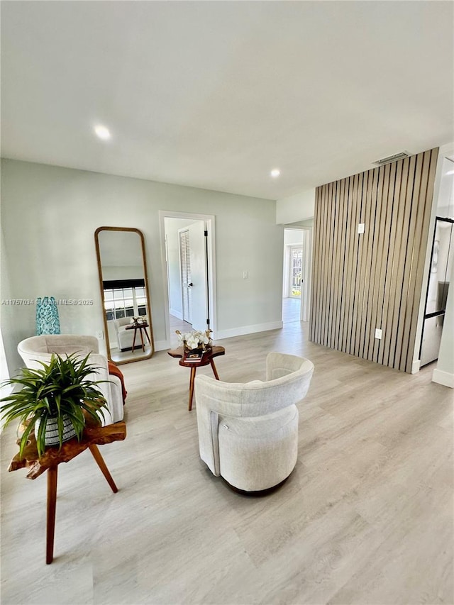 living room with light wood-type flooring, visible vents, baseboards, and recessed lighting