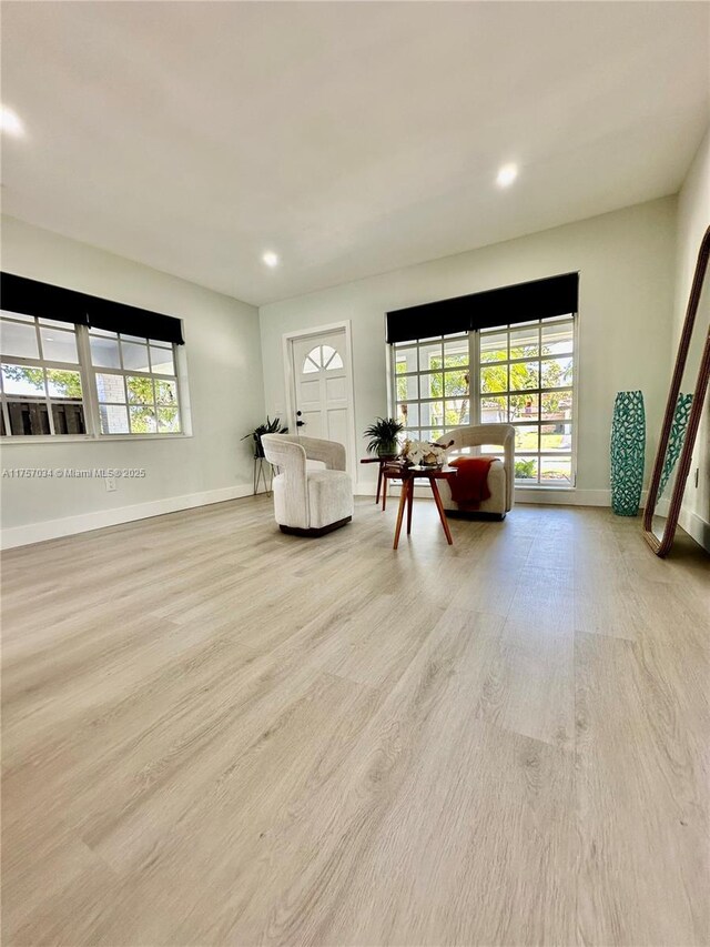 living area with baseboards, light wood-type flooring, visible vents, and recessed lighting