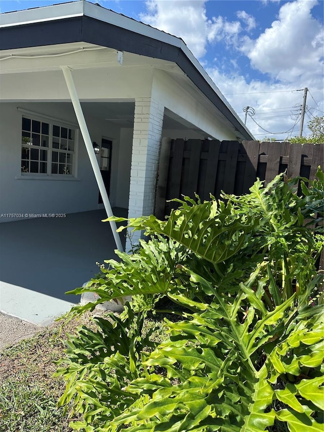 view of side of home with brick siding and fence