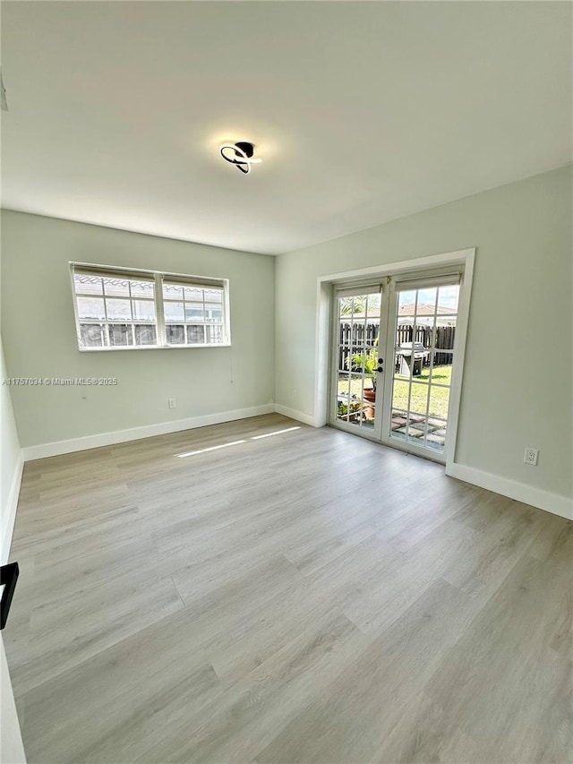 empty room with baseboards, wood finished floors, and french doors