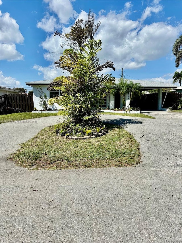 view of front of home featuring gravel driveway, fence, and a carport