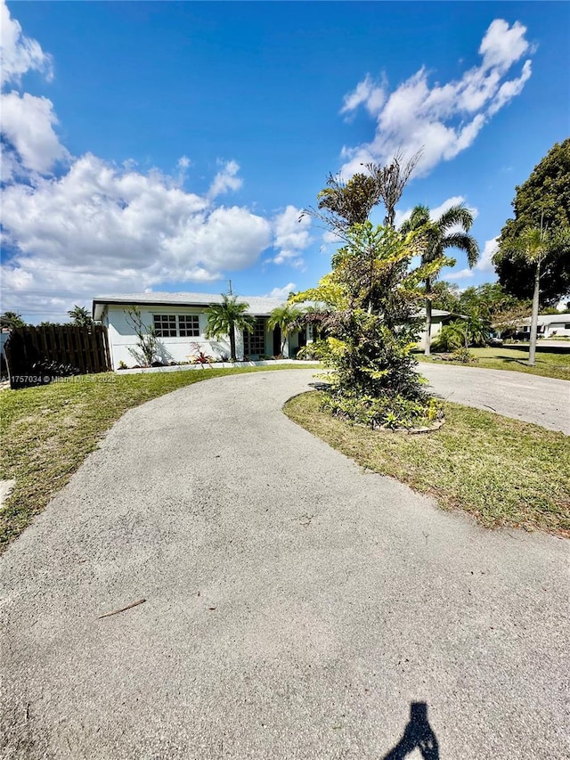 view of front of home featuring fence and curved driveway