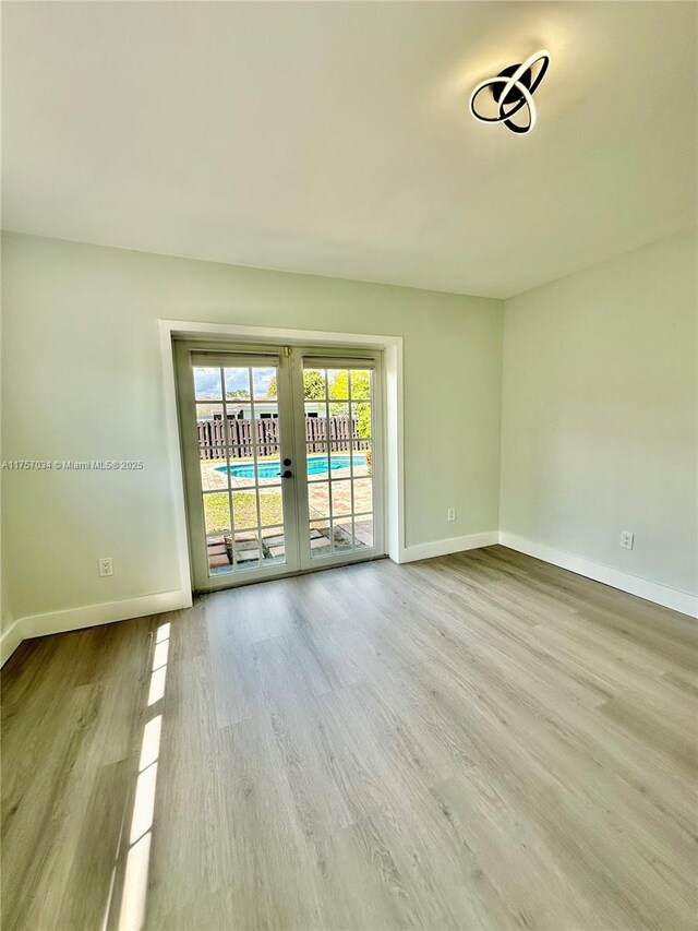 empty room featuring french doors, baseboards, and wood finished floors