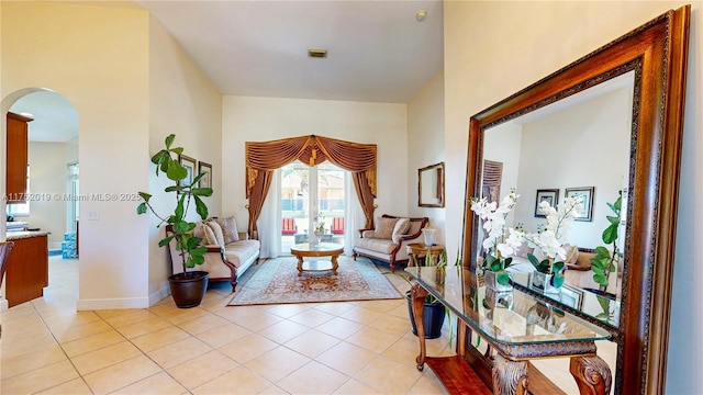 living area with arched walkways, baseboards, and light tile patterned floors