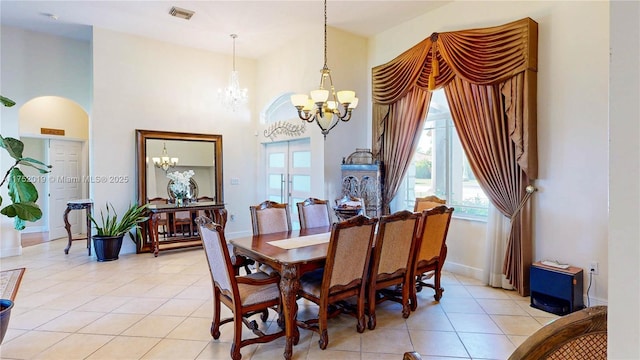 dining room featuring light tile patterned floors, a high ceiling, visible vents, and an inviting chandelier