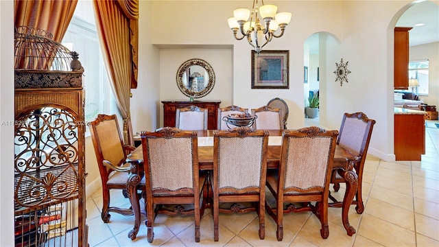 dining area with arched walkways, light tile patterned floors, baseboards, and an inviting chandelier