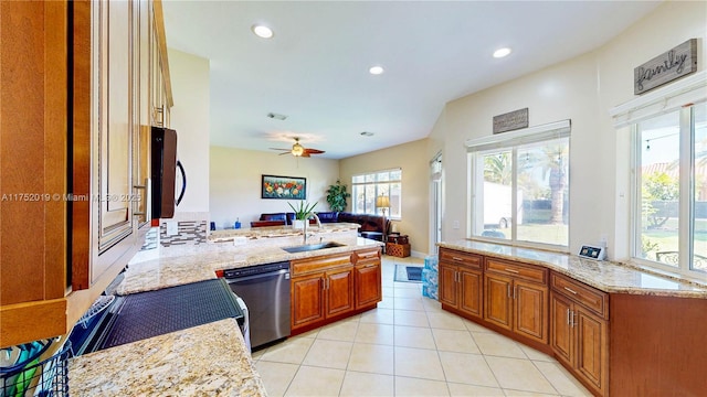 kitchen with a peninsula, a sink, open floor plan, light stone countertops, and dishwasher