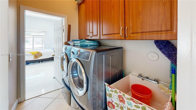 laundry area with light tile patterned flooring, washing machine and dryer, and cabinet space