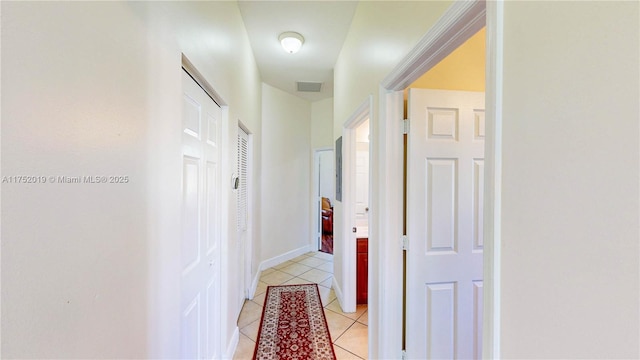 hall featuring baseboards, visible vents, and light tile patterned flooring