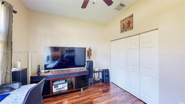 living area with a ceiling fan, visible vents, and wood finished floors