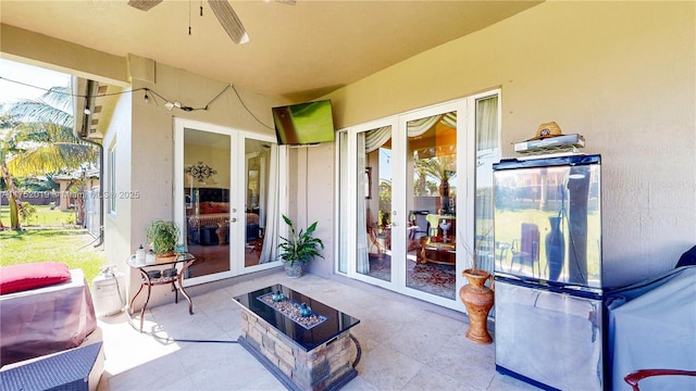 view of patio / terrace with a fire pit, ceiling fan, and french doors