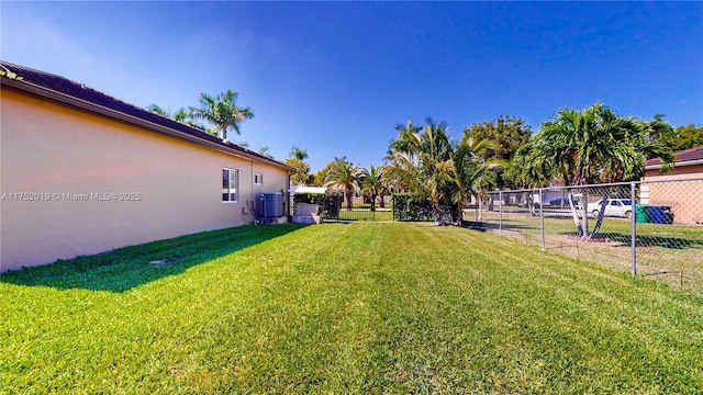 view of yard with central AC unit and fence