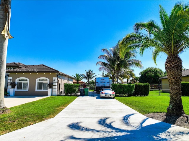 exterior space with driveway, a yard, fence, and stucco siding