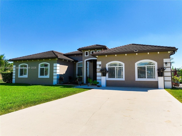 mediterranean / spanish home featuring a front yard, a tile roof, driveway, and stucco siding