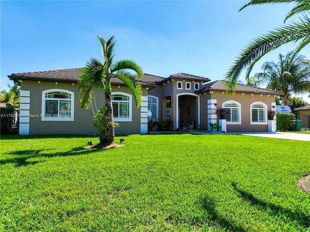 mediterranean / spanish-style house featuring driveway, a front lawn, a tile roof, and stucco siding