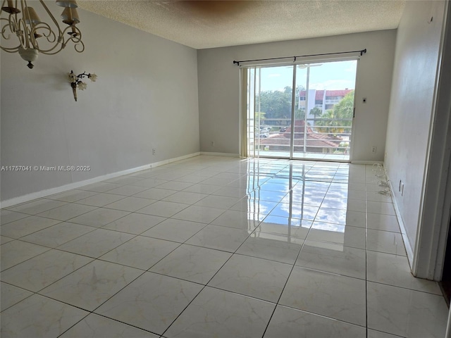 empty room featuring light tile patterned floors, baseboards, a chandelier, and a textured ceiling