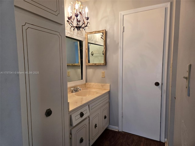 bathroom with baseboards, wood finished floors, vanity, and a notable chandelier