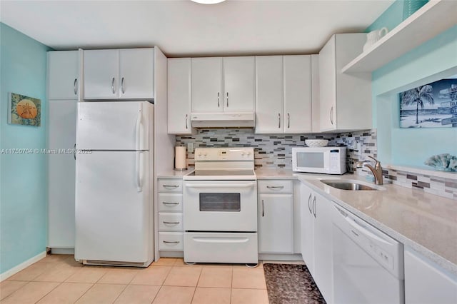 kitchen with white appliances, light tile patterned floors, light countertops, under cabinet range hood, and a sink