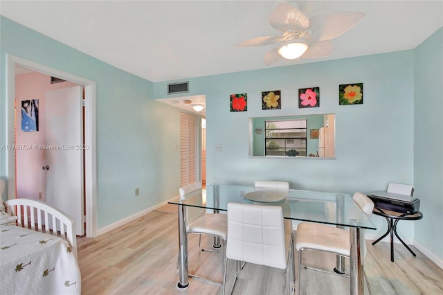 dining room featuring a ceiling fan, visible vents, baseboards, and wood finished floors