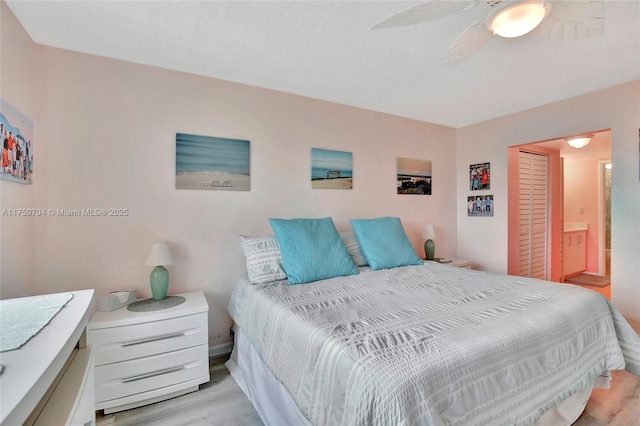 bedroom with a ceiling fan, ensuite bathroom, and wood finished floors