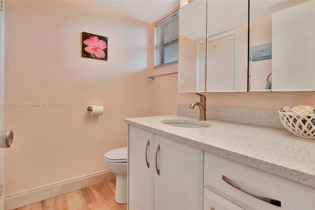 bathroom featuring baseboards, vanity, toilet, and wood finished floors