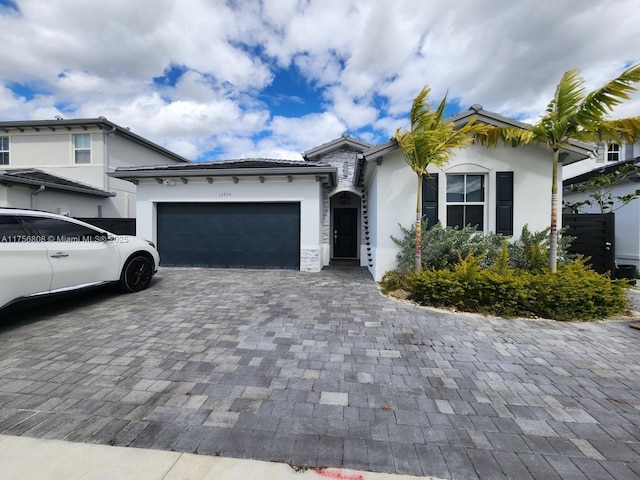 view of front facade with stone siding, decorative driveway, an attached garage, and stucco siding